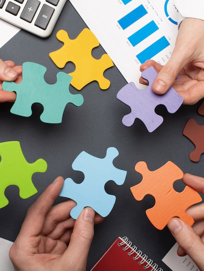 Verschillende kleuren puzzelstukjes die door handen worden vastgehouden